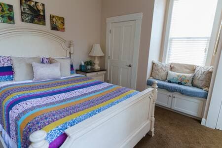 Queen bedroom on first floor has high ceilings and tall windows. Full bathroom is across the hall.