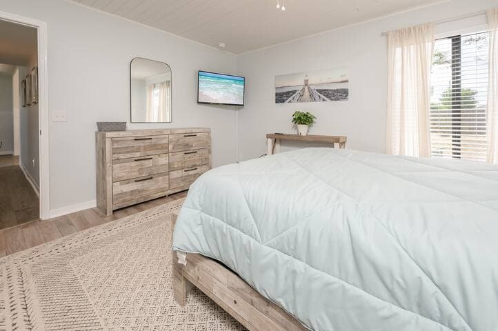 Another view of our first floor primary bedroom which includes a flat-screen tv for lazy mornings in bed (or late night movies). Escape to your private sanctuary which includes an adjoining bath.