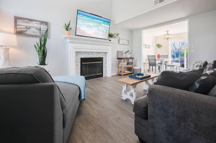 Bright and cozy living room featuring a stylish fireplace and modern decor creates a relaxing ambiance. The open-concept design flows into the dining area, perfect for enjoying meals with family or friends.