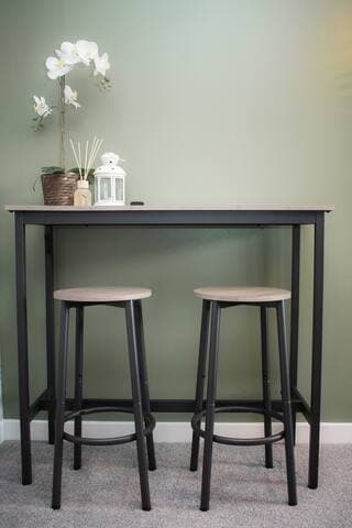 Living room with large comfortable L shaped sofa, additional chair, 65" Smart TV, football/foosball table and small table with stools.