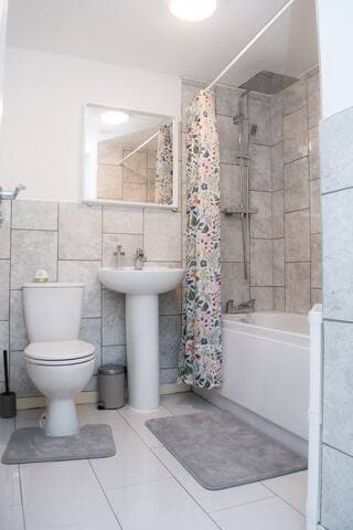 Bathroom with large mirror and full sized bath with a two-way rainfall shower head and separate shower head.