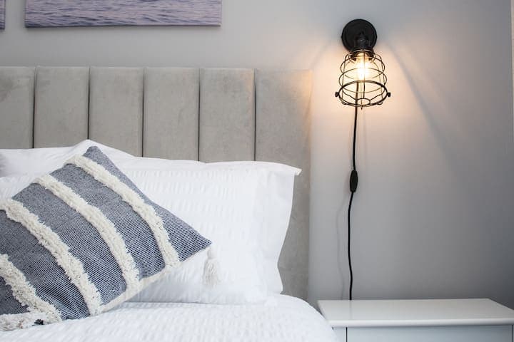 Twin bedroom with two single beds with individual bedside units, 4-way power adaptors with USB chargers and clothes storage with wooden hangers and drawers. A shelf contains a selection of mini board games.