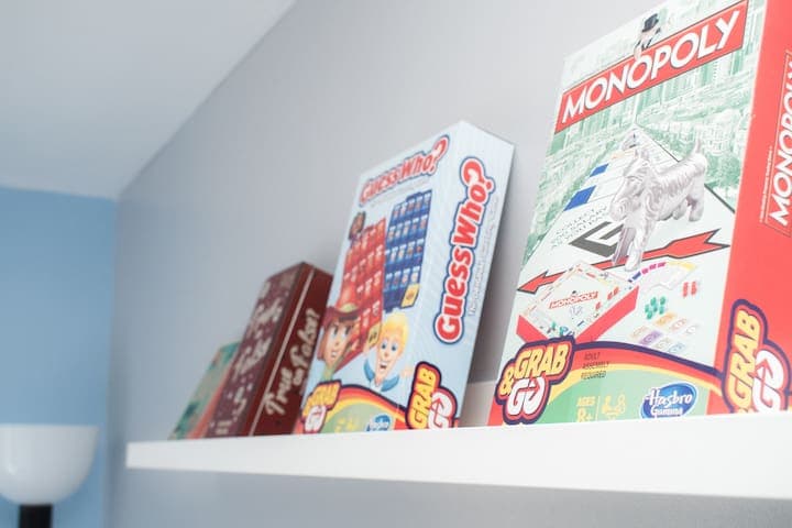 Twin bedroom with two single beds with individual bedside units, 4-way power adaptors with USB chargers and clothes storage with wooden hangers and drawers. A shelf contains a selection of mini board games.