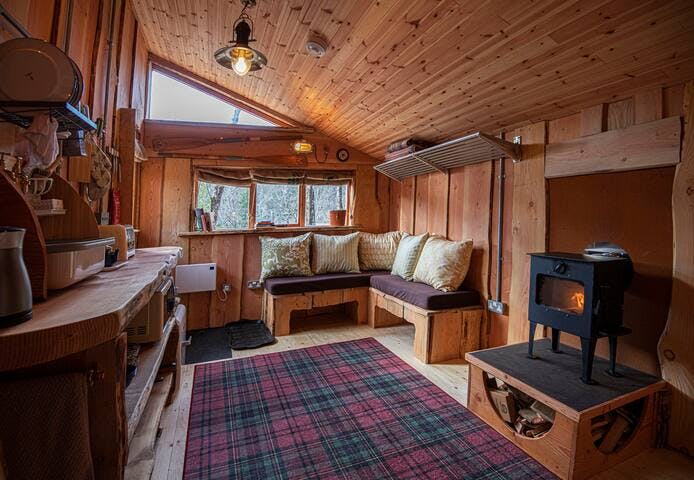 Quirky cabin interior with one-off features - salvaged maritime lighting, bespoke cladding and seating, organic cotton cushions, 'Ruggable' washable rugs, bespoke wee stove, blackout blinds made from Fairtrade coffee sacks, minimal plastic use