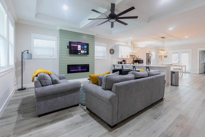 Indulge in relaxation and serenity in this spacious living room. Sink into plush couches, enjoy a 50" smart TV, cozy up to the electric fireplace, and bask in natural light. A perfect getaway for ultimate comfort.