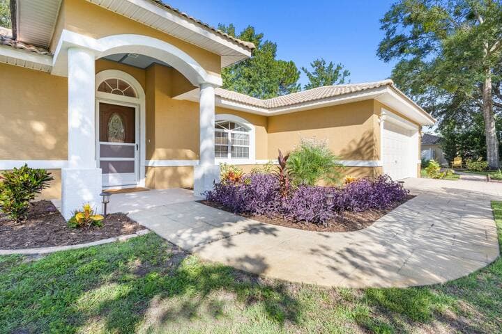 Freshly painted exterior of the home from the front yard with views of a couple of the planting beds.
