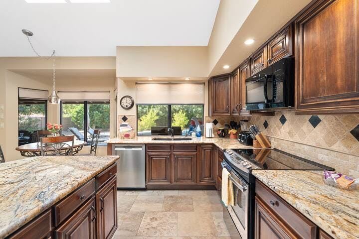 Top-of-the-line appliances complement a cozy breakfast nook offering serene backyard views.