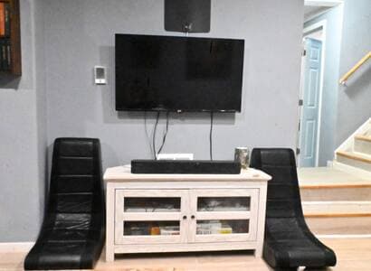 Living Room | Gaming Chairs + Roku TV | Projector + Retro Games Gaming chairs tuck against the wall and can be pulled out for use. 47" Roku TV with soundbar, 80" pull-down projector above. Cabinet holds PS1, SNES, and several board games.