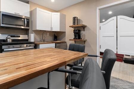 Kitchen | Double Swing Doors + Barstools New double swing doors and four barstools. From left: oven with microwave above, sink, dishwasher, coffee station with spice rack overhead.